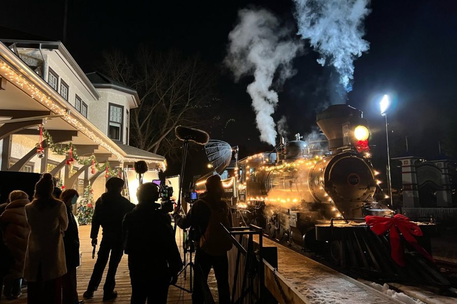 A film crew works on filming a Christmas movie at the Train Station at Fort Edmonton Park. They are on the platform looking at the 1919 Baldwin Locomotive 107 train.